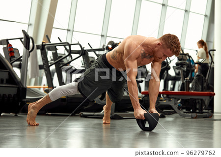 Muscular man doing push up in the gym. Athletic man doing exercise with push up. Man workout push up in the gym. Sport fitness and healthy lifestyle. 96279762