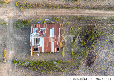 Aerial view over destroyed house with broken roof after tornado or storm. Top down, drone shot Aerial view over destroyed house with broken roof after tornado or storm. Top down, drone shot 96280844