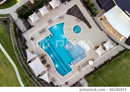 Aerial shot of green lawn, swimming pool, lounge area near beautiful mansion in the courtyard in the summertime. Aerial shot of green lawn, swimming pool, lounge area near beautiful mansion in the courtyard in the summertime. 96280855