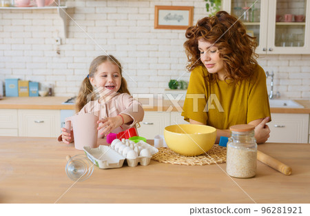 Mother and daughter prepare a cake together in the kitchen 96281921