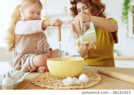 Mother and daughter prepare a cake together in the kitchen 96281925