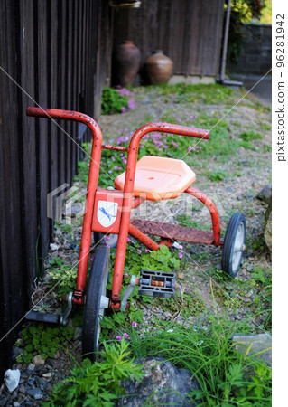 一輛舊三輪車放在花園裡 96281942