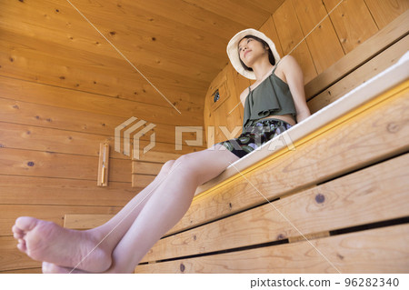 A young woman wearing a sauna hat and entering a sauna 96282340