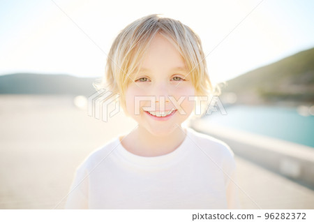 Portrait of cheerful smiling schoolboy child by sea during summer holidays on sunny day. Concept of freedom, happy childhood and limitless possibilities. 96282372