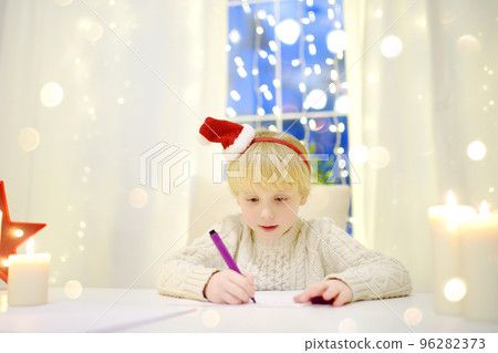 Little boy writing the letter to Santa. Child dreams of a gift that he can receive. Magic mail of Santa Claus. Traditions around New Year and Christmas Holidays. 96282373