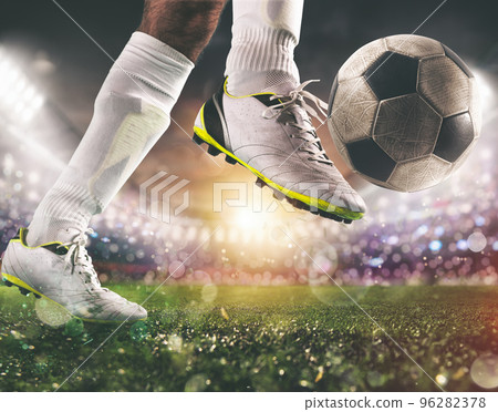 Close up of a soccer scene with player in a white uniform kicking the ball with power Close up of a soccer scene with player in a white uniform kicking the ball with power 96282378