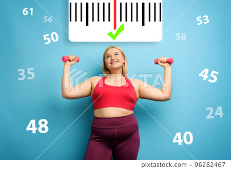 Fat girl does gym at home with satisfied expression because she decrease her weight. Cyan background 96282467