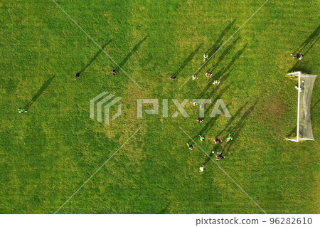 Aerial drone view of a sports field and a football team that practices tactical schemes. Football players practice kicking the ball and defending. Football is a great sport for active man Aerial drone view of a sports field and a football team that practices tactical schemes. Football players practice kicking the ball and defending. Football is a great sport for active man 96282610