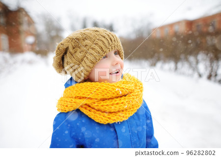 Little boy walking on sunny winter day. Child dressed in a warm clothes, hat, hand gloves and scarf. Active outdoors leisure for kids on nature among driven snow 96282802