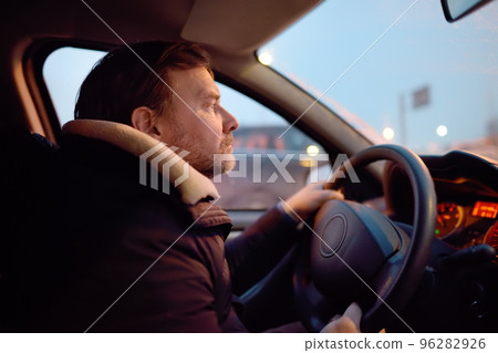 Mature man driver riding a car in city on cold winter evening. Taxi driver waiting client passanger. Inside view. Mature man driver riding a car in city on cold winter evening. Taxi driver waiting client passanger. Inside view. 96282926