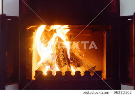 Burning fireplace is in Alpine chalet. The concept of wintertime vacations. Winter holidays - Christmas and New Year. Cozy evening in cold weather Burning fireplace is in Alpine chalet. The concept of wintertime vacations. Winter holidays - Christmas and New Year. Cozy evening in cold weather 96283102