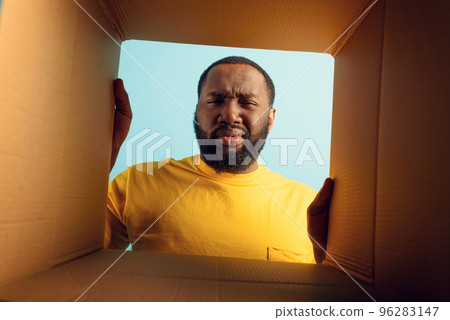 Man have doubt and he is disgusted about what is inside a package. concept of online shop fraud Man have doubt and he is disgusted about what is inside a package. concept of online shop fraud 96283147