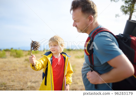 Cute schoolchild and his mature father hiking together and exploring nature. Little boy and his dad spend quality family time on summer vacation. Father's Day. Cute schoolchild and his mature father hiking together and exploring nature. Little boy and his dad spend quality family time on summer vacation. Father's Day. 96283179