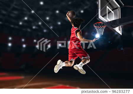 Basketball player in red uniform jumping high to make a slam dunk to the basket 96283277