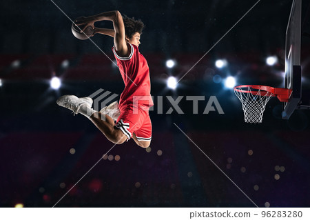 Basketball player in red uniform jumping high to make a slam dunk to the basket 96283280