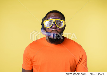 Man with snorkeling mask is scared to go underwater. yellow background Man with snorkeling mask is scared to go underwater. yellow background 96283521