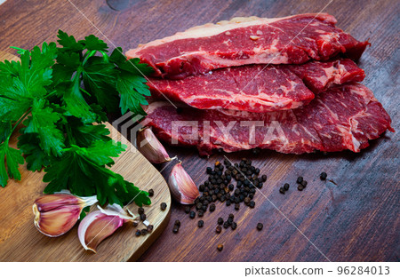 close up of pieces of marbled beef served with parley on wooden table 96284013