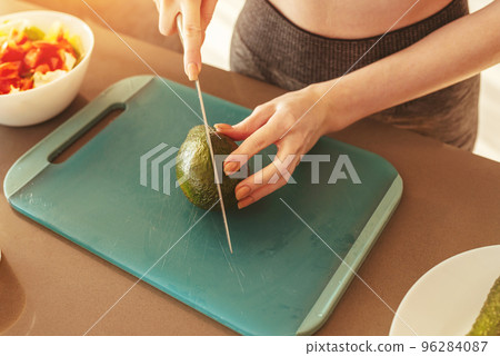 Woman in the home kitchen cutting an avocado for a healthy eating Woman in the home kitchen cutting an avocado for a healthy eating 96284087