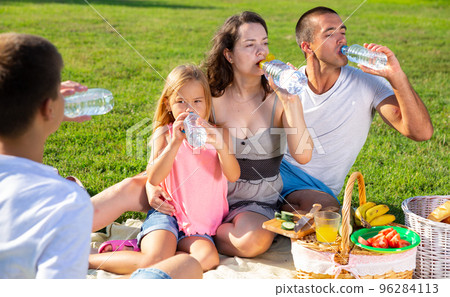 Parents with two teenagers enjoying delicious meal on the picnic Parents with two teenagers enjoying delicious meal on the picnic 96284113