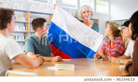 Pupils having lesson of geography. Female teacher discussing with children about national flag of Russia in library Pupils having lesson of geography. Female teacher discussing with children about national flag of Russia in library 96284619