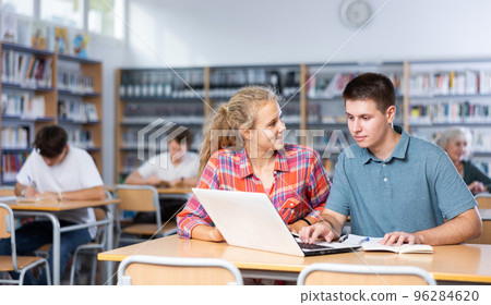 European schoolgirl with a classmate in the library is preparing for lessons European schoolgirl with a classmate in the library is preparing for lessons 96284620