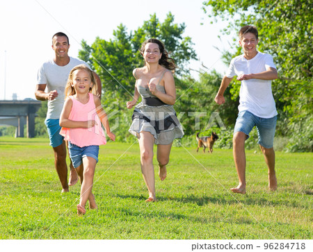 Happy family of four running on grass at summer park Happy family of four running on grass at summer park 96284718