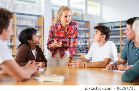 Group of schoolchildren in the school library, discussing something 96284733