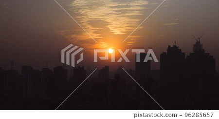 The sun setting behind the buildings The sun setting behind the buildings 96285657