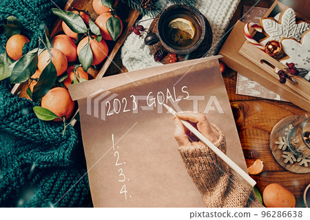 Women's hands write goals for the year on a decorated Christmas table Women's hands write goals for the year on a decorated Christmas table 96286638