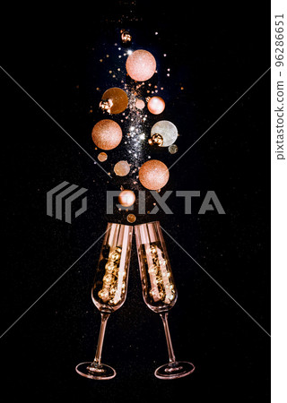 Glasses of champagne and golden shiny holiday decor, balloons, black background Glasses of champagne and golden shiny holiday decor, balloons, black background 96286651