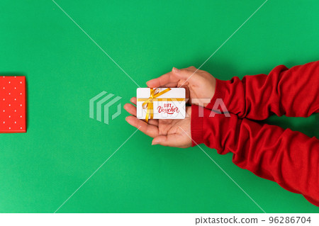 Gift voucher or bonus card template with ribbon in female hands, green background 96286704