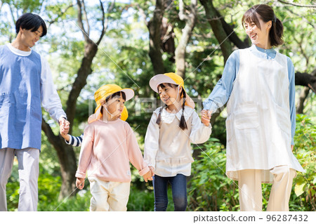 Childcare worker and kindergarten strolling in the park 96287432