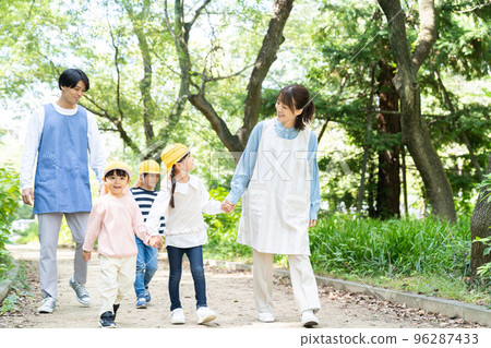 Childcare worker and kindergarten strolling in the park 96287433