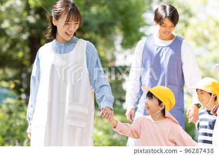 Childcare worker and kindergarten strolling in the park Childcare worker and kindergarten strolling in the park 96287438