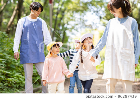 Childcare worker and kindergarten strolling in the park 96287439