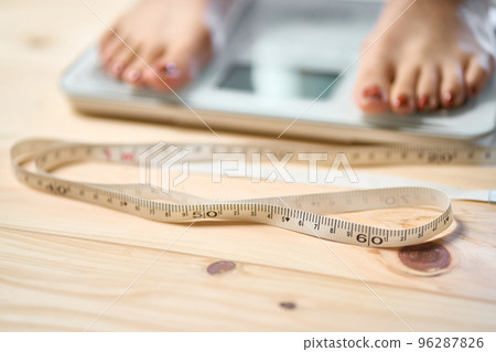 Feet of a woman on a measure and scale 96287826