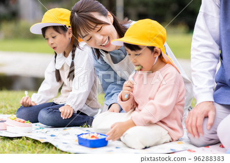 A nursery teacher and a child who eat lunch in the park 96288383