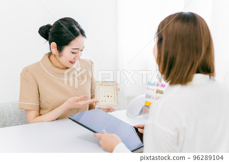 Asian woman holding a tablet with a manicurist showing samples and consulting design options at a nail salon Asian woman holding a tablet with a manicurist showing samples and consulting design options at a nail salon 96289104