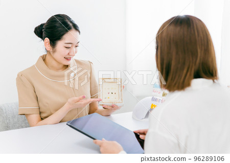 Asian woman holding a tablet with a manicurist showing samples and consulting design options at a nail salon Asian woman holding a tablet with a manicurist showing samples and consulting design options at a nail salon 96289106