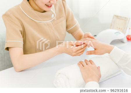 Asian manicurist checking nail condition in nail salon Asian manicurist checking nail condition in nail salon 96291616