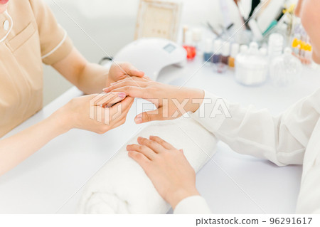 Asian manicurist checking nail condition in nail salon 96291617