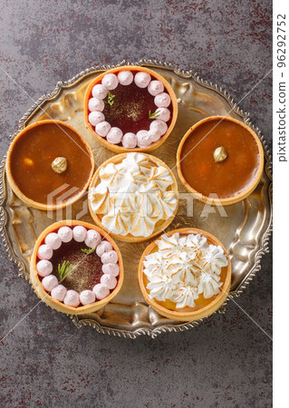 Festive mix tartlets with lemon curd, raspberry curd, nuts and chocolate close-up. Vertical top view 96292752