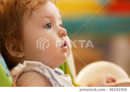 The baby sits on a highchair and waits for the 96292908