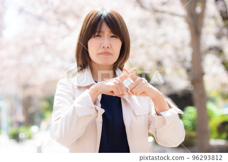 Woman doing hand sign outdoors in spring with cherry blossoms 96293812