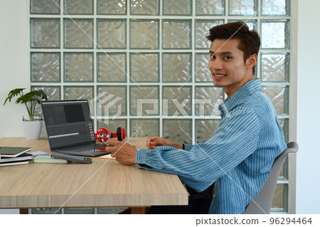 Asian male video editor working with footage and sound on laptop at modern creative office 96294464