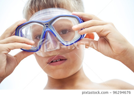 Teen schoolboy puts on blue goggles to swim exploring flora and fauna of sea. Teenager ready to enjoy summer holidays swimming underwater 96294676