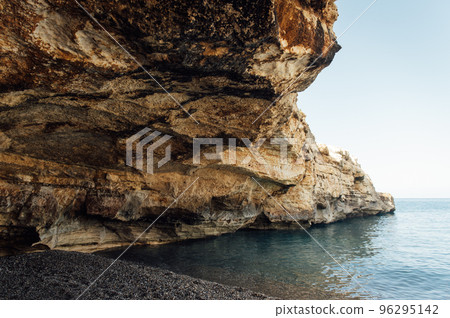 Massive rocks sink into the water on a pebble beach 96295142