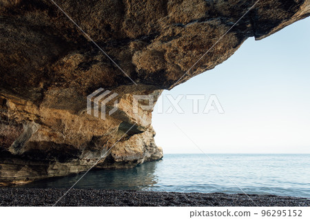 Massive rocks sink into the water on a pebble beach Massive rocks sink into the water on a pebble beach 96295152