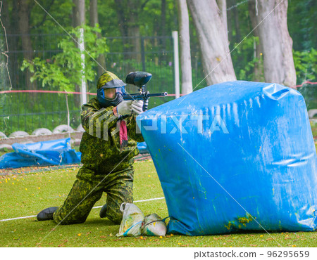 paintball sport player in protective uniform and mask playing with gun outdoors 96295659