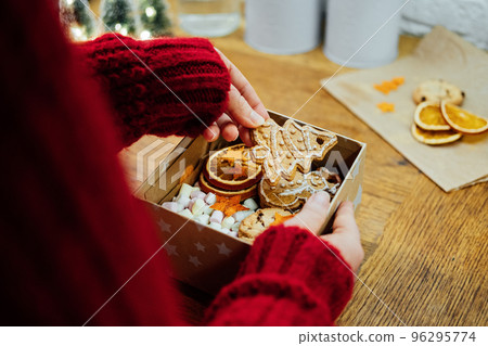 Christmas Homemade Sweet Hampers in female hands. Woman hsnds holding Christmas Sweet Gift Box. Festive treats Gift Hamper Idea for Adults and Kids. Box with Homemade different cookies Christmas Homemade Sweet Hampers in female hands. Woman hsnds holding Christmas Sweet Gift Box. Festive treats Gift Hamper Idea for Adults and Kids. Box with Homemade different cookies 96295774